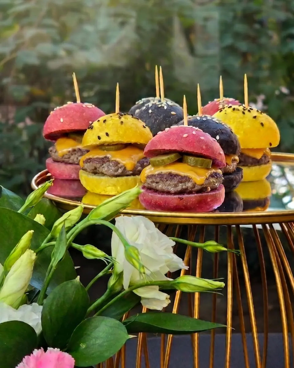 Bocados de mini hamburguesa de vacuno en pan de color para banquetería y eventos premium.